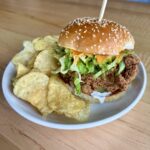 Buffalo ranch chicken sandwich with crispy buttermilk chicken, shredded lettuce, pickles, ranch, and buffalo sauce on a brioche bun.