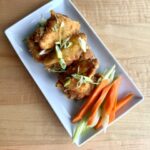 Twice-fried chicken wings tossed in Carolina Gold BBQ sauce and garnished with seasonal vegetables and green onion.