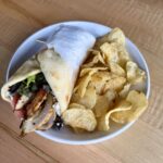 Chicken shawarma served with tzatziki, mixed greens, tomato, feta cheese, and naan bread.