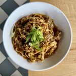 Dandan noodles with Chinese pork sausage, tagliatelle noodles, crushed peanuts, cabbage, scallions, peanut sauce, and chili oil.