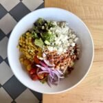 Summer Cobb salad with mixed greens, corn, red onion, tomato, bacon, queso fresco, and chipotle ranch dressing.