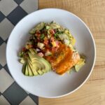 Seared salmon topped with peach pico and avocado, served with coconut rice and a zucchini and squash medley.